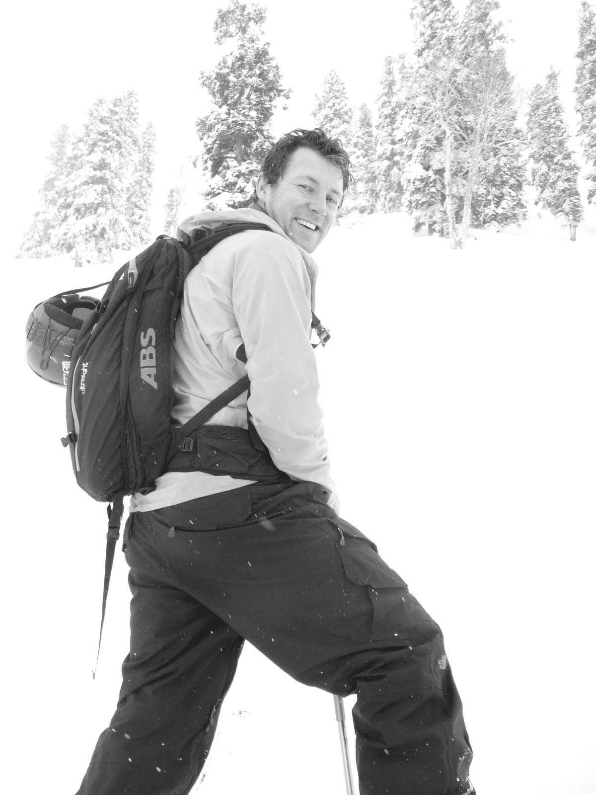 Carlyle Jenkins in the mountains, carrying ski equipment in falling snow.